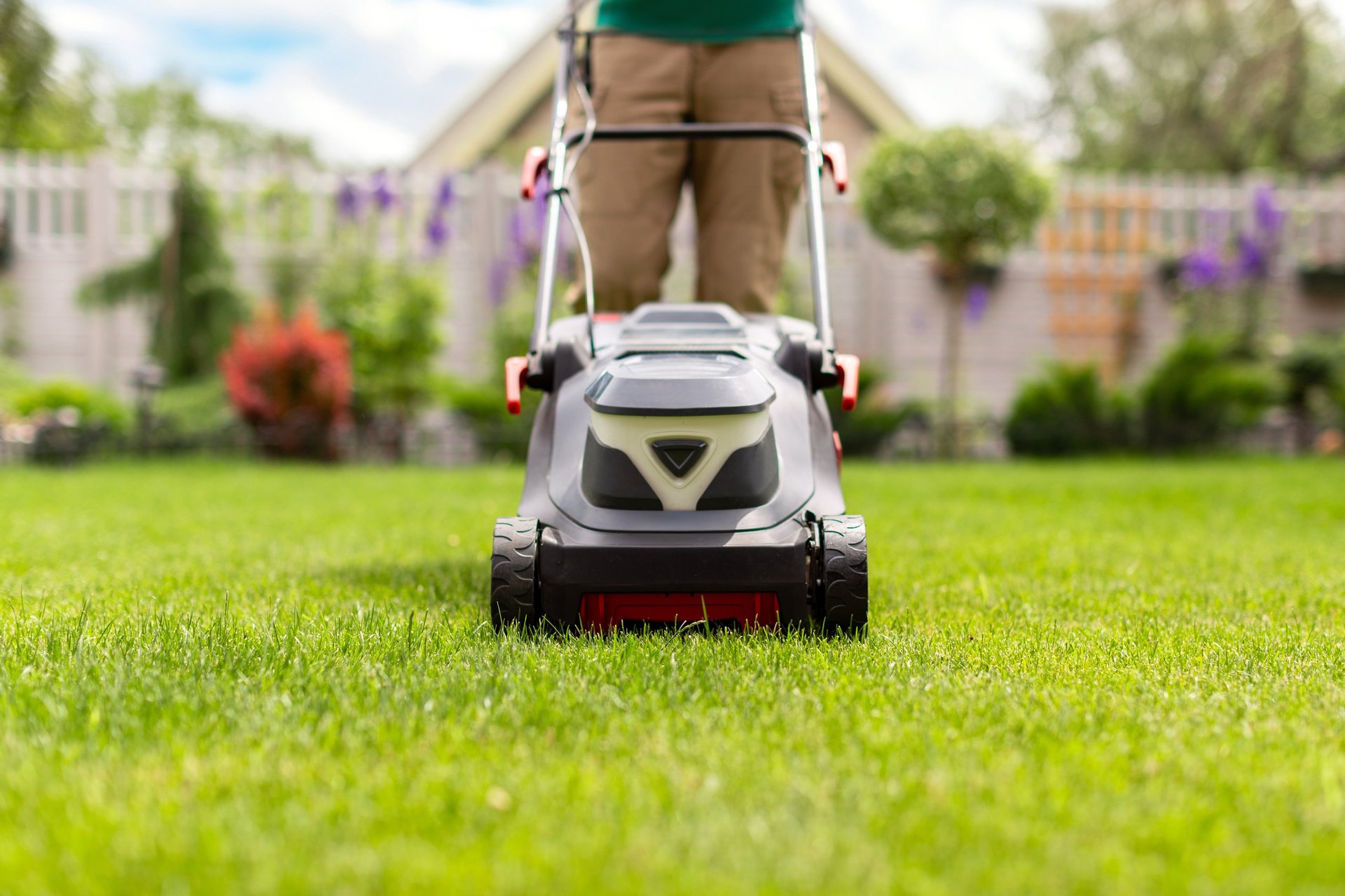 Modern lawn mower with male gardener working in home garden