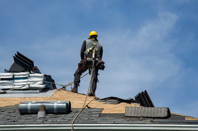 Construction worker using pneumatic nailer applying roofing materials