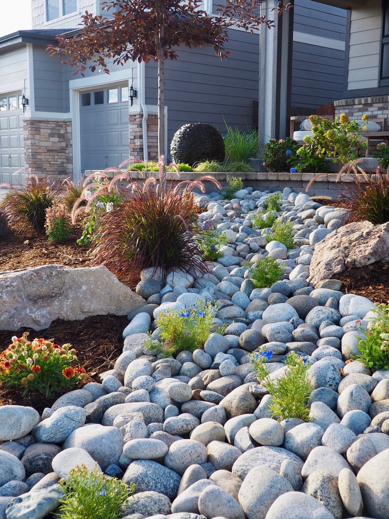 Home xeriscape design with a cobblestone dry creek that flows down the center giving it appearance of a natural stream